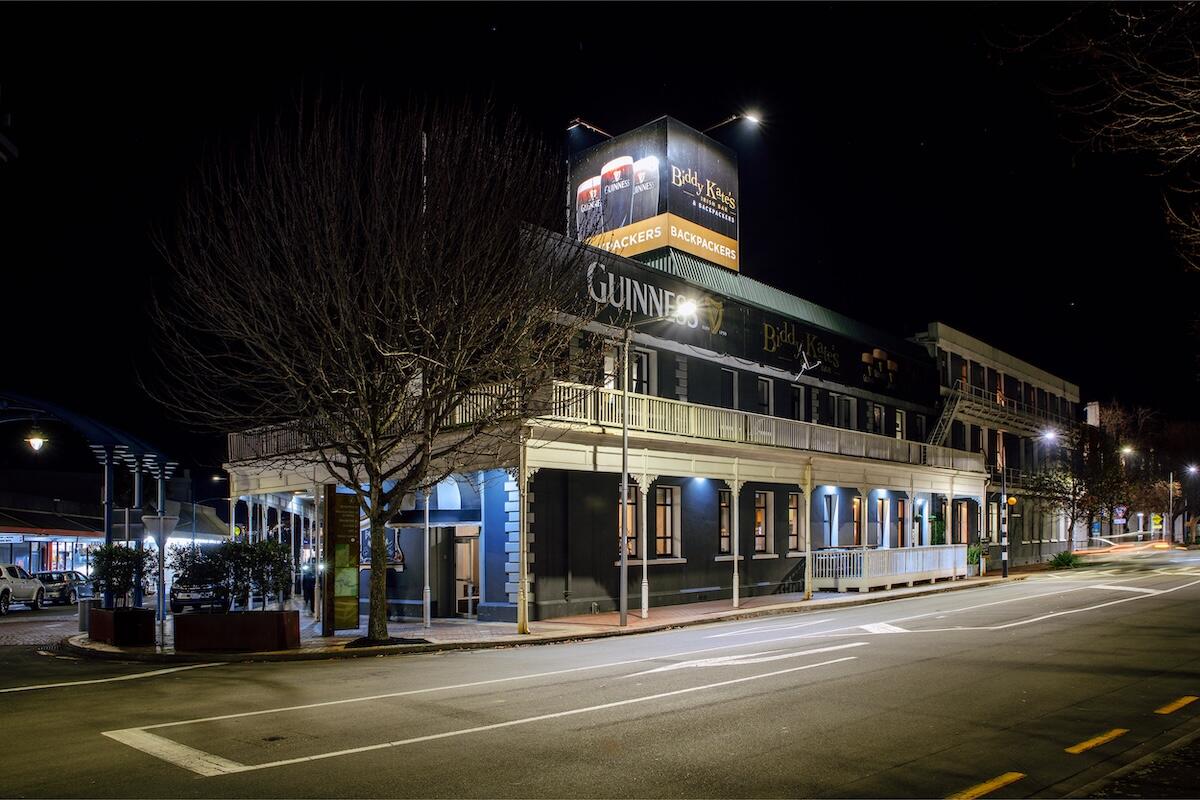 Biddy Kate's Cafe Bar exterior on Market Street, Blenheim at night, with the Guinness sign lit up