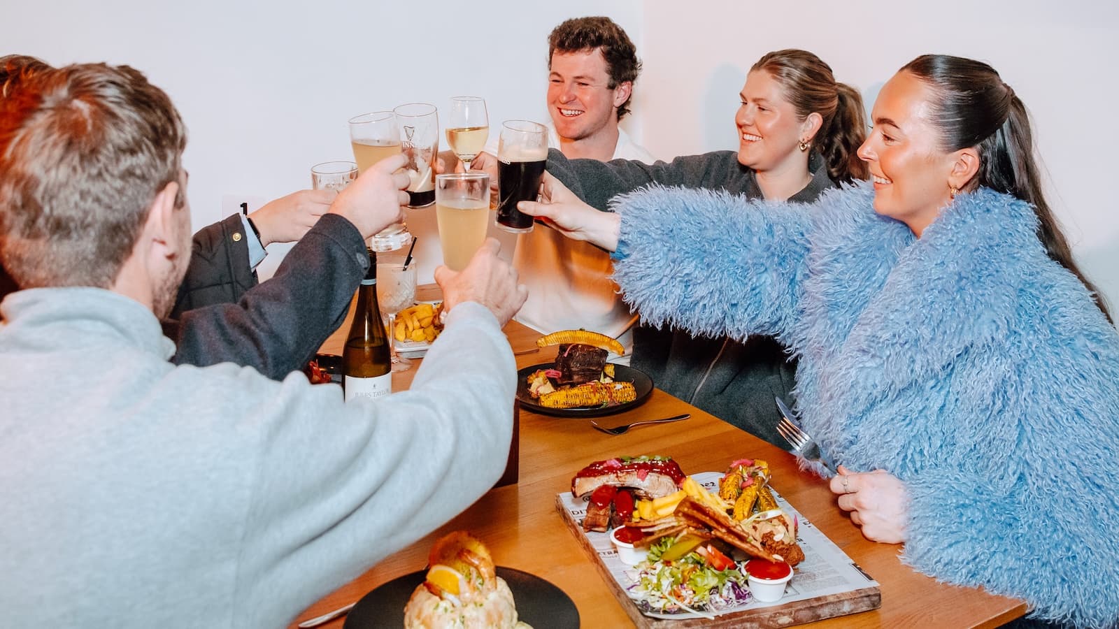 A group of friends raising glasses and celebrating at Biddy Kate's Cafe Bar, Blenheim