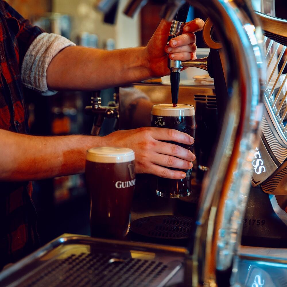 Bartender pouring a Guinness on tap at Biddy Kate's Bar, Blenheim